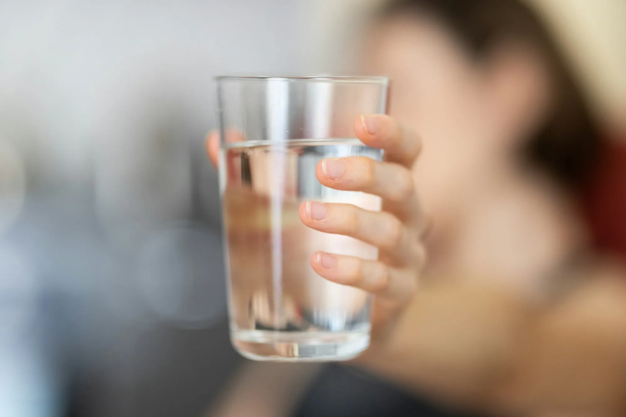 Hand holding a clear glass of drinking water