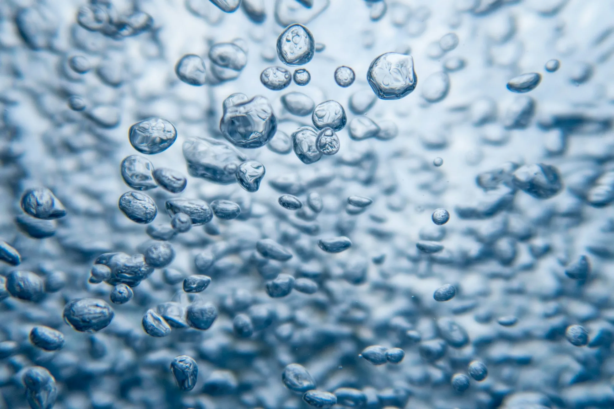 Fine bubbles rising through clear blue water