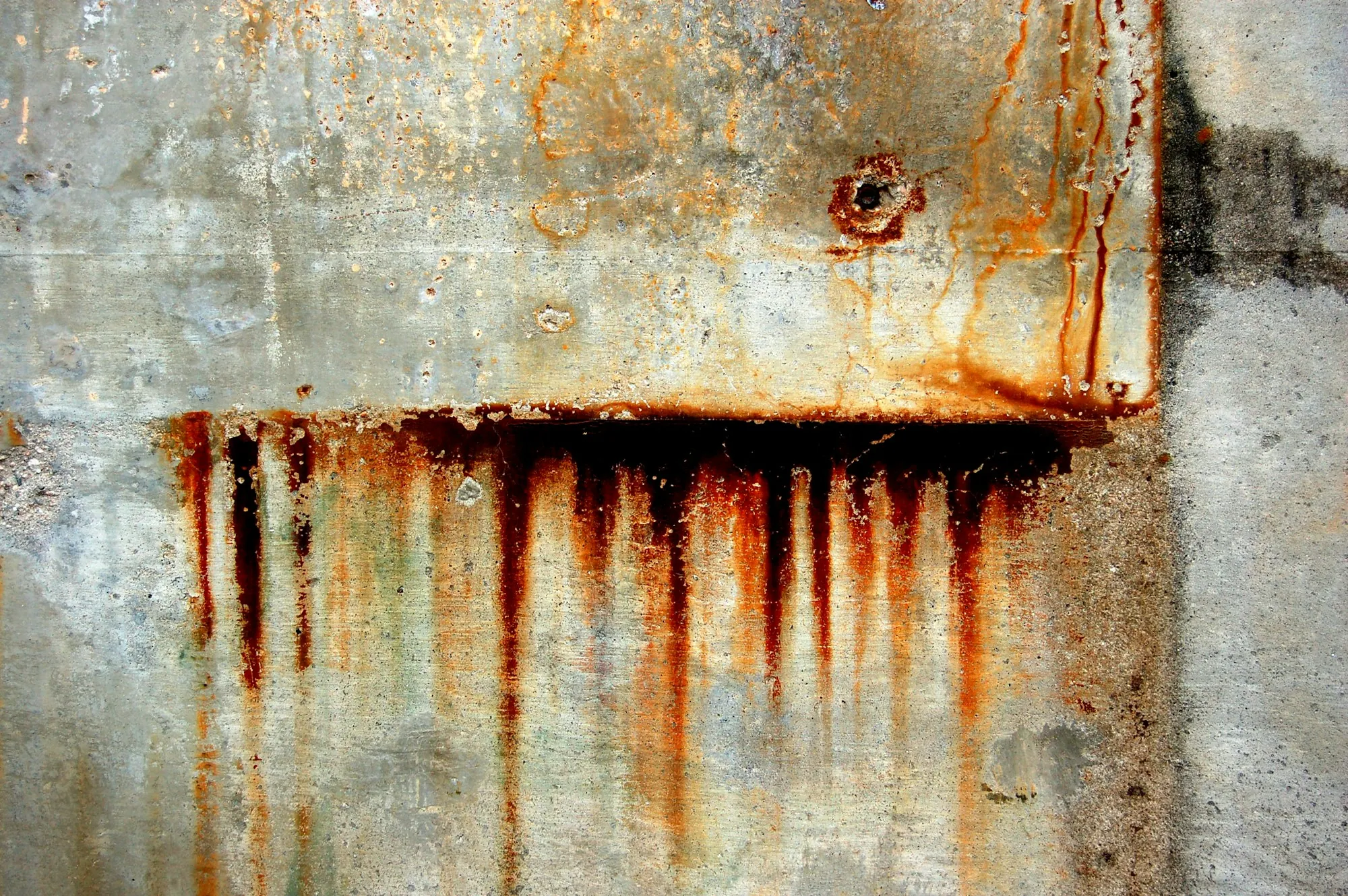 Orange rust stains streaking down a light wall