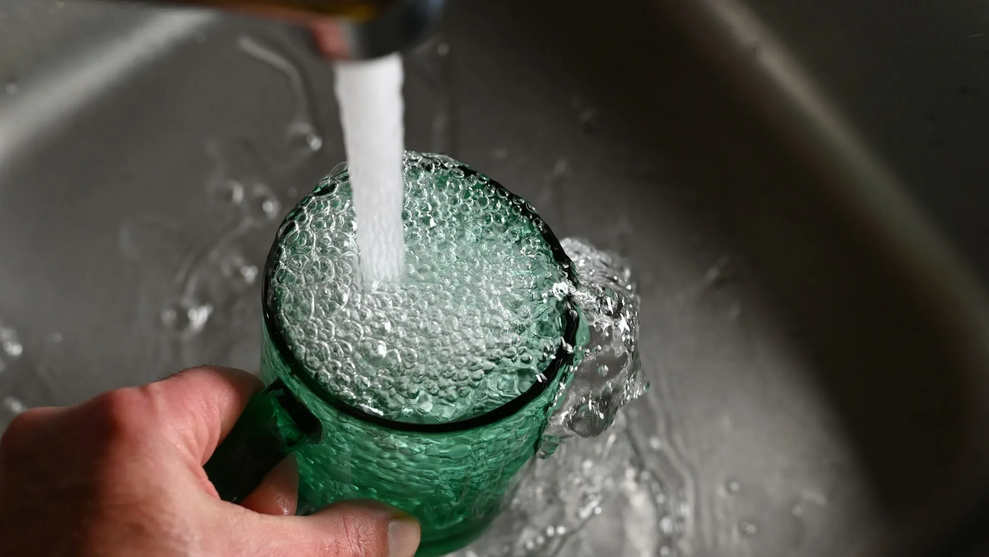 Glass being filled with clear water from a kitchen tap