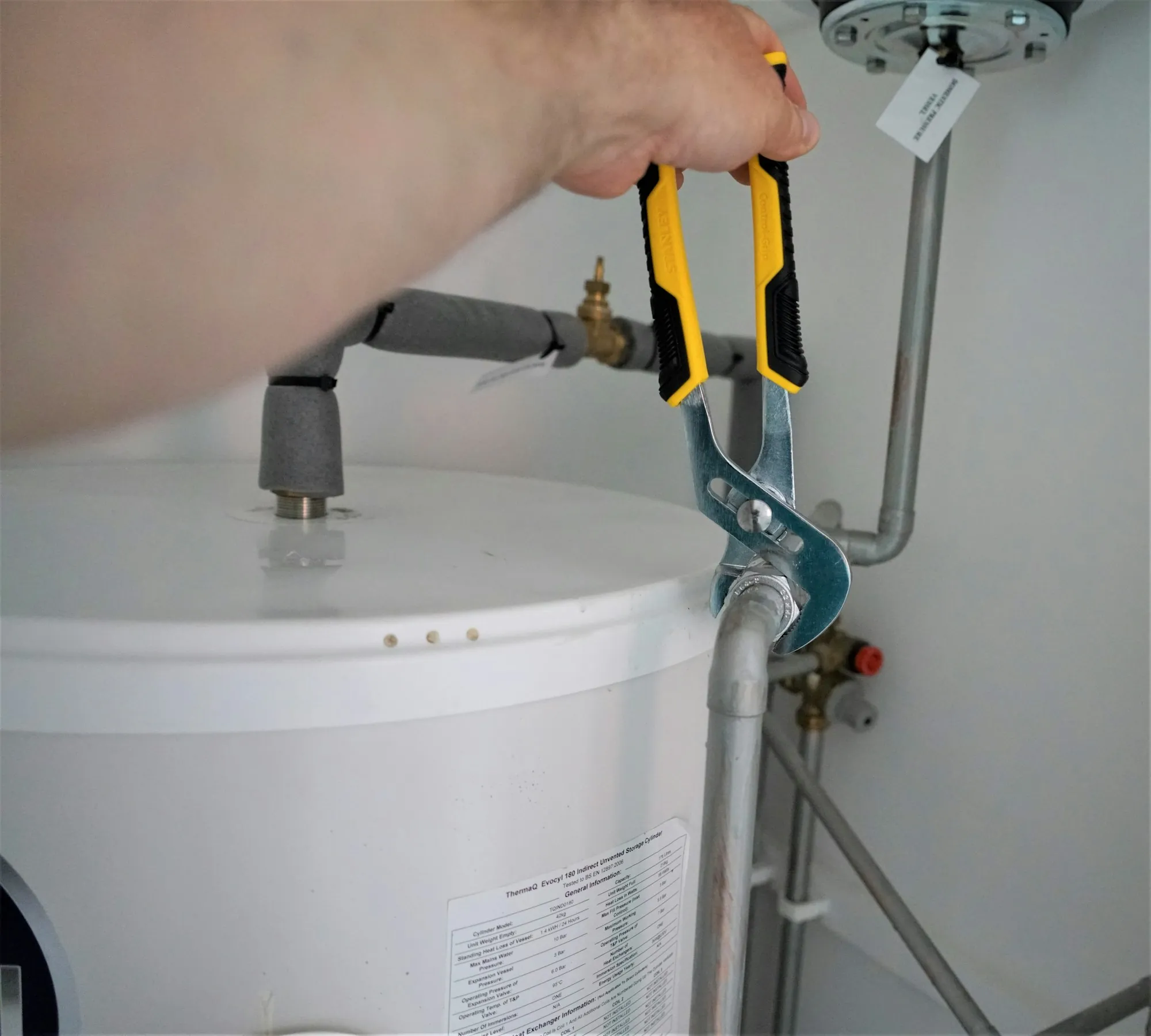Hands tightening a fitting on a residential water heater