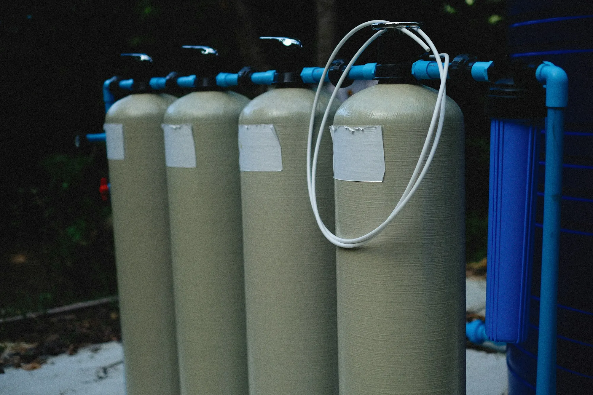 Row of water filtration tanks connected with blue piping