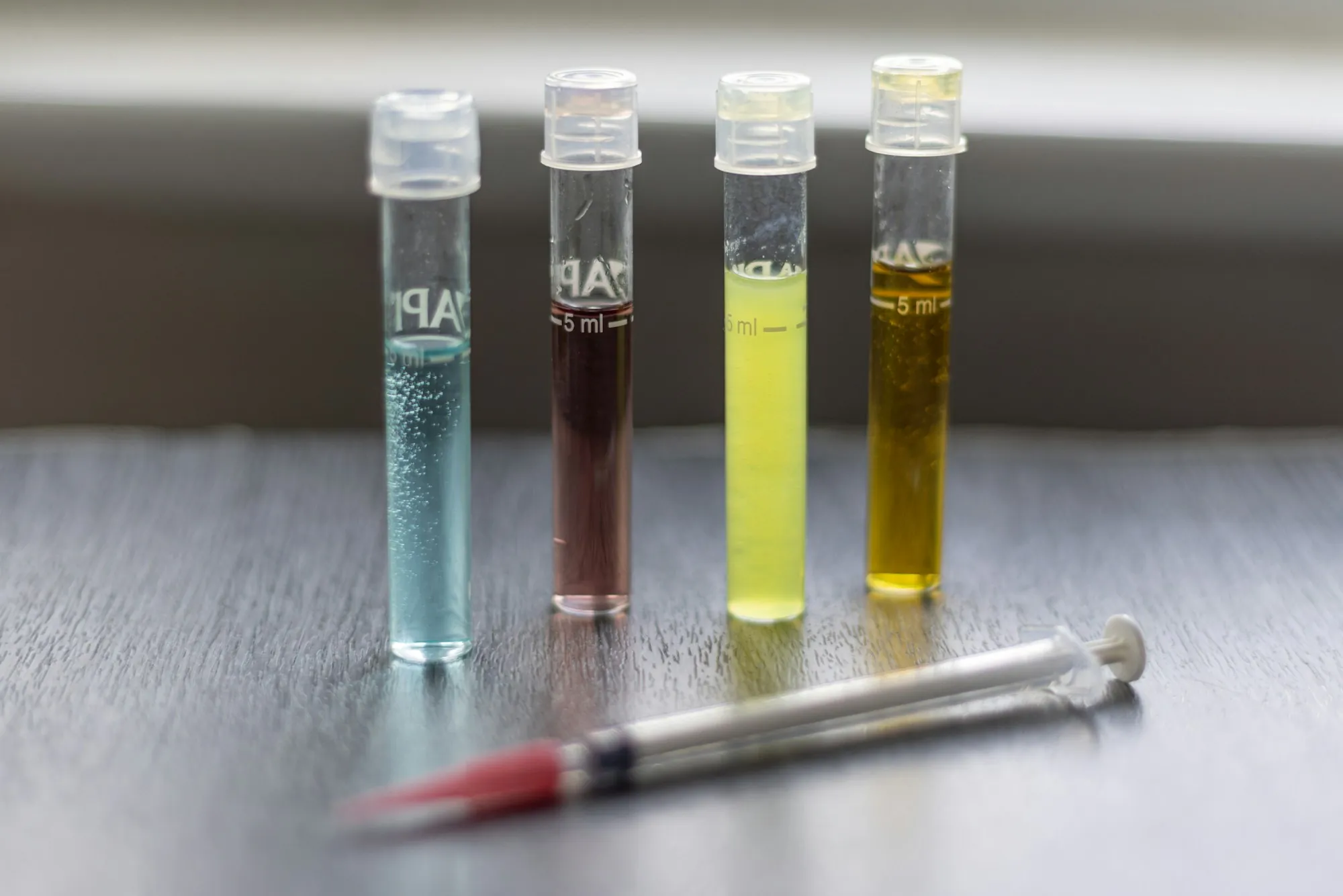 Four water sample test tubes beside a dropper