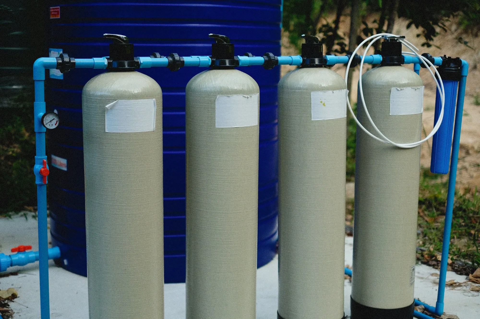 Whole-home water treatment tanks plumbed together outdoors
